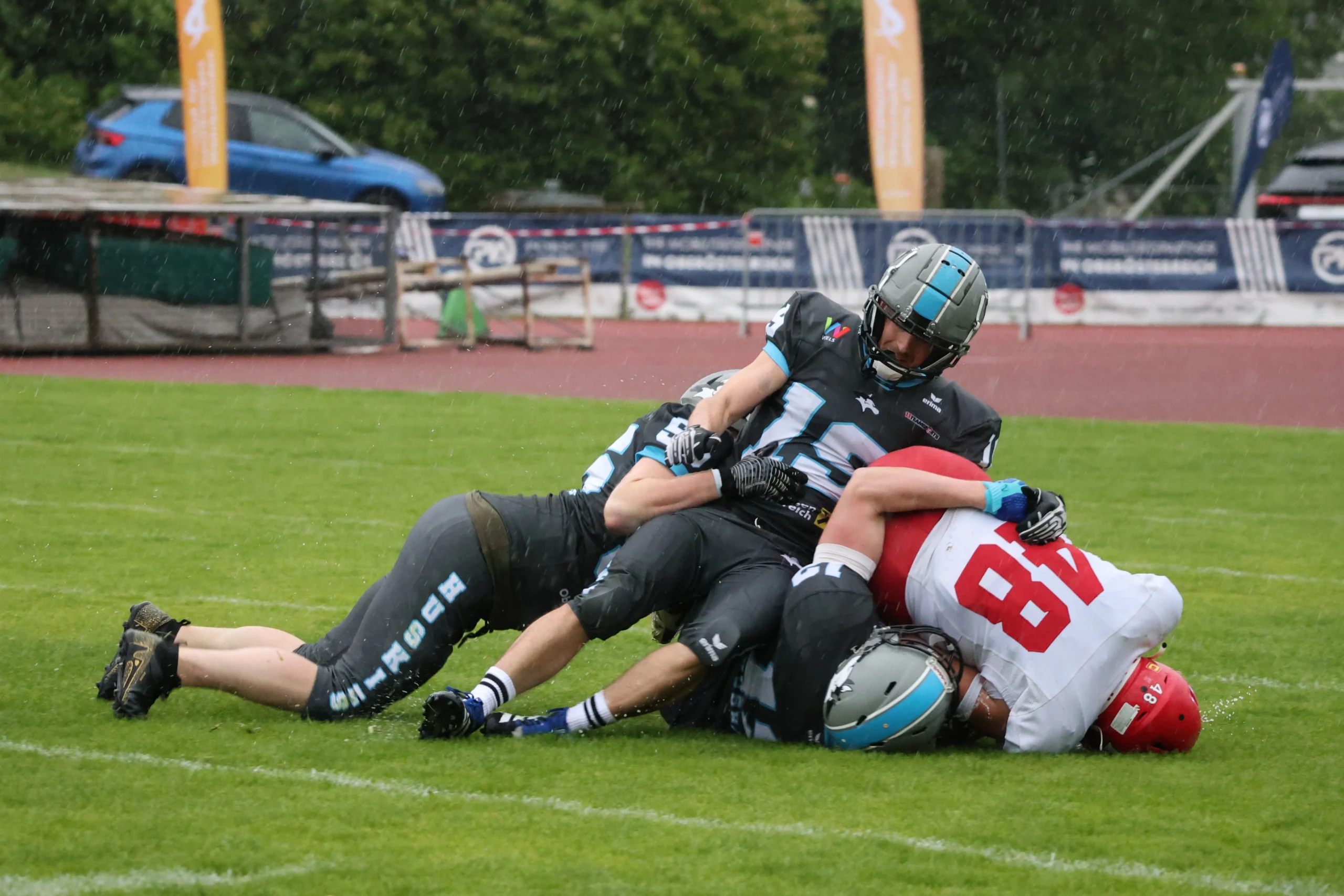 Red Tigers Nr. 48 im Tackle – Huskies Wels vs. Red Tigers Red Tigers Spieler Nr. 48 wird von zwei Huskies Wels Verteidigern getackelt – intensives Duell im AFL DIV I Spiel 2026